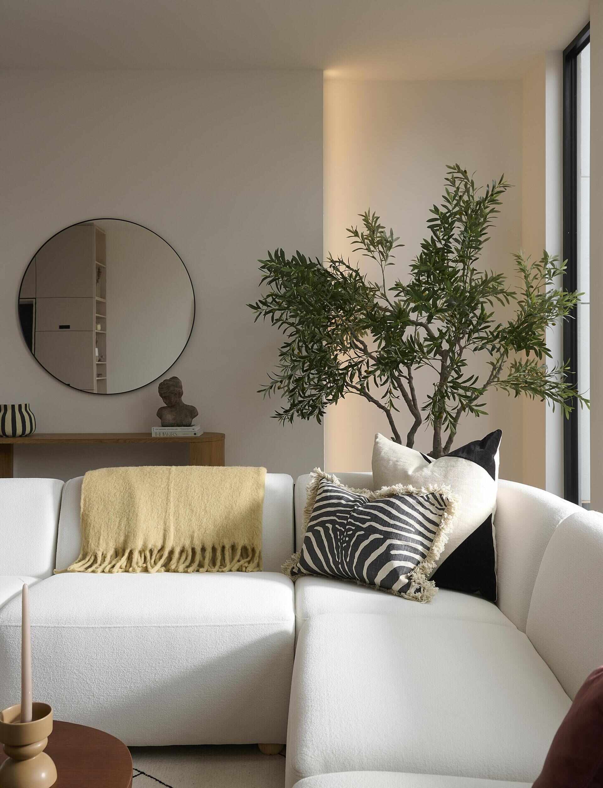 At the back of the home, the living area opens fully to the outdoors through a sliding glass door. Three skylights soften the room with overhead light. A freestanding black fireplace sits on a black brick and white oak hearth.