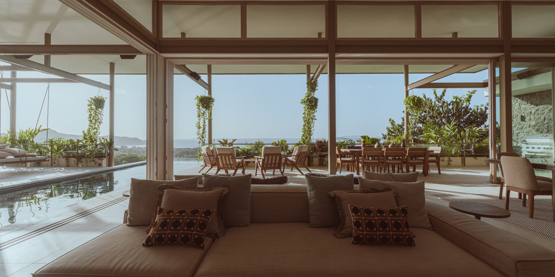 The main social spaces are placed on the upper level to capture ocean views and natural ventilation. The living room, with its double-sided couch, opens in multiple directions and feels integrated with the planted terrace and cantilevered pool. 