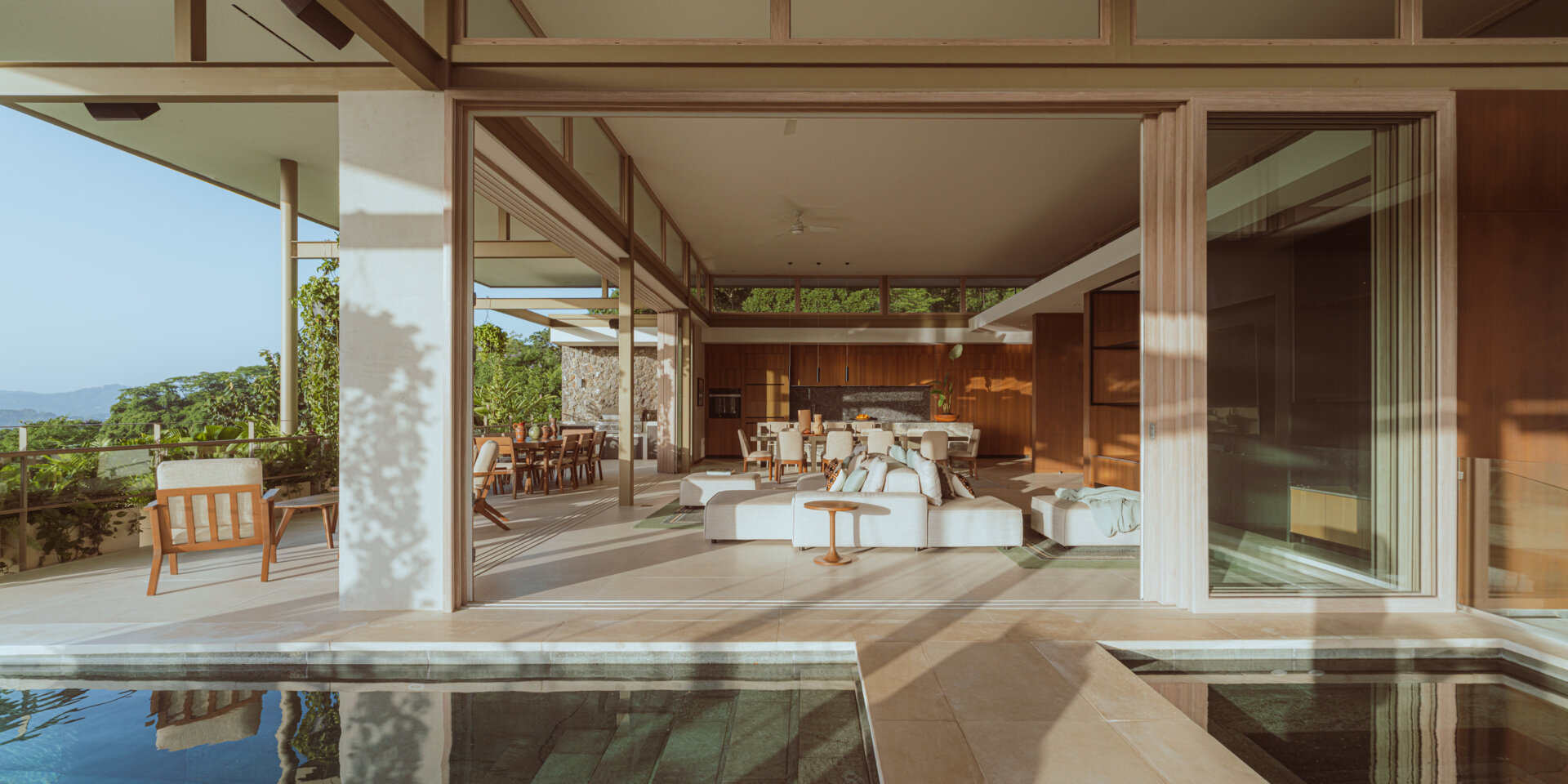 The main social spaces are placed on the upper level to capture ocean views and natural ventilation. The living room, with its double-sided couch, opens in multiple directions and feels integrated with the planted terrace and cantilevered pool. 