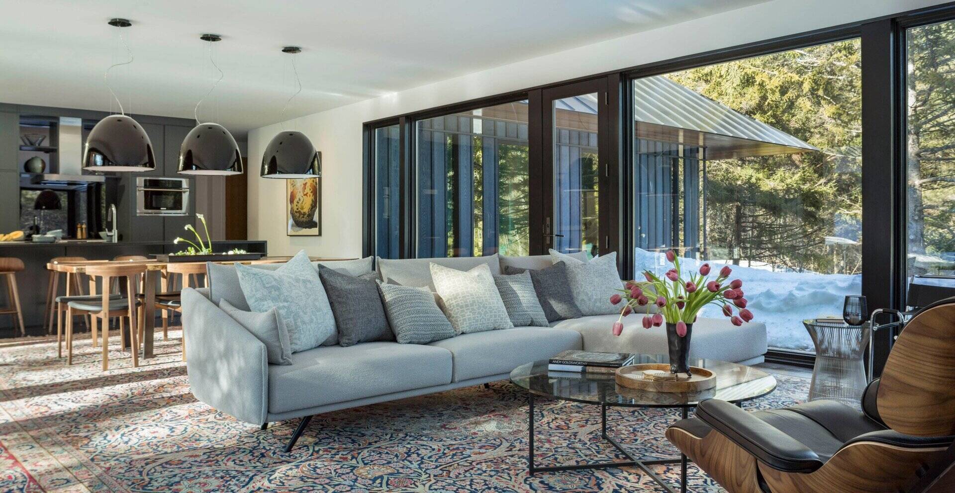A sleek horizontal fireplace anchors the open living room, surrounded by large windows that fill the space with light and meadow views.