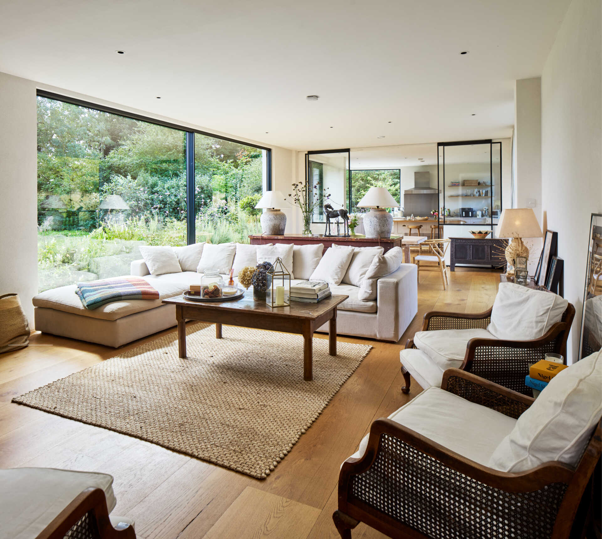 Large windows in the open living room frame the meadow. Light becomes part of the experience in every season. The interior materials keep the feeling grounded and warm, with natural tones echoing the surroundings.
