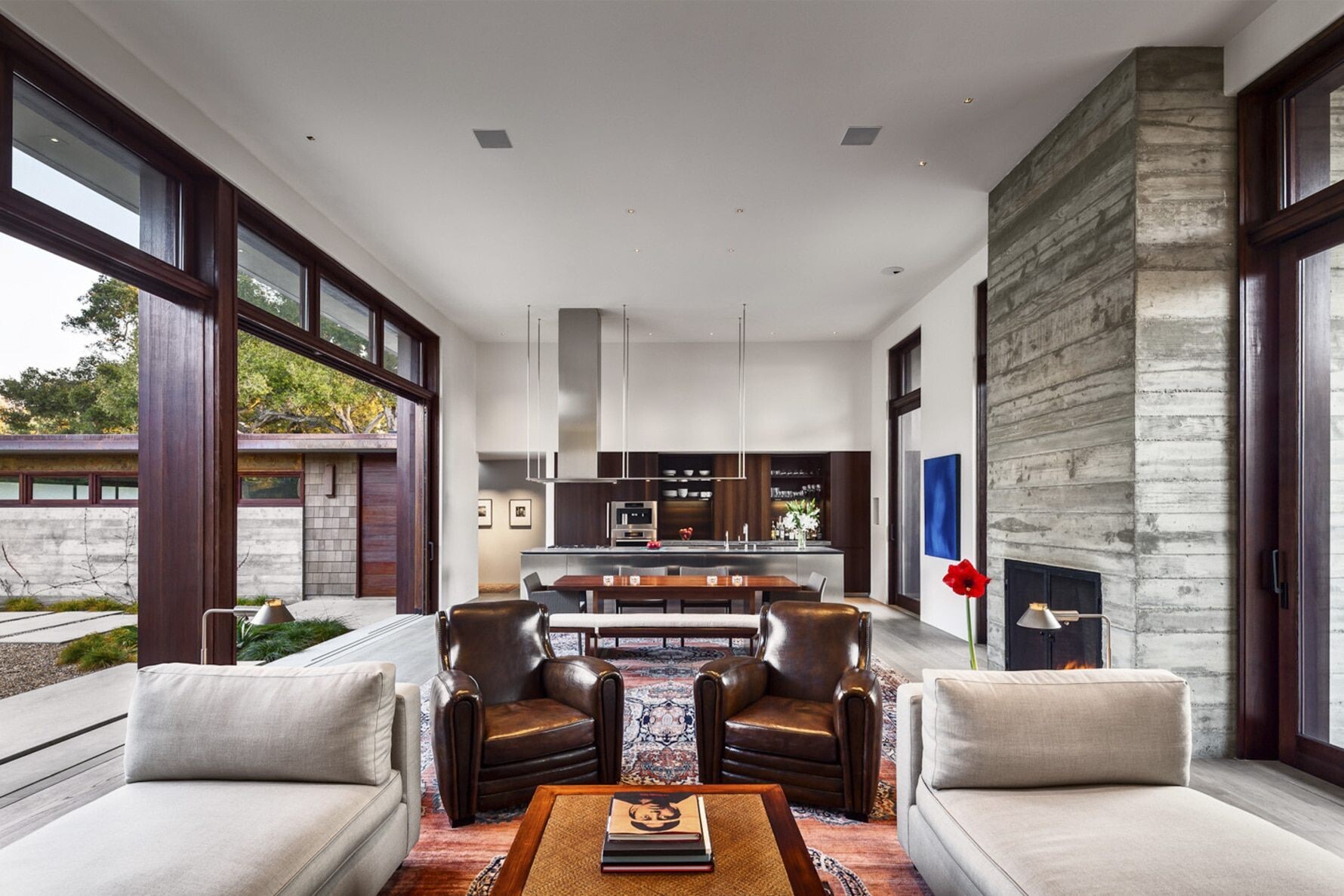 The living area blends high ceilings, natural light, and a statement concrete fireplace for a serene yet modern look.