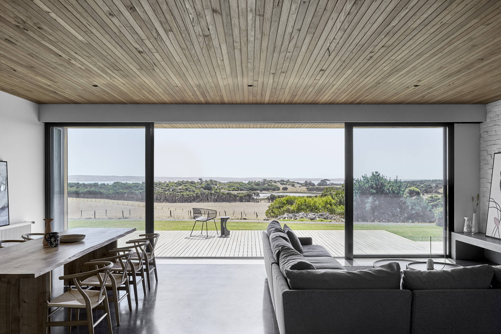 The kitchen, living and dining areas share one generous space, making it easy for the family to spread out or come together. Doors open to a wide timber deck, where views of the coastline stretch out toward the horizon.