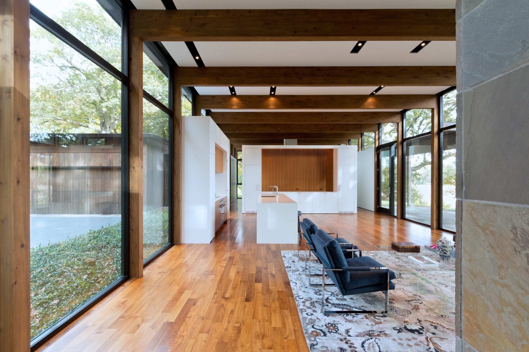 Minimal interiors with walnut floors, exposed beams and a warm modern palette.