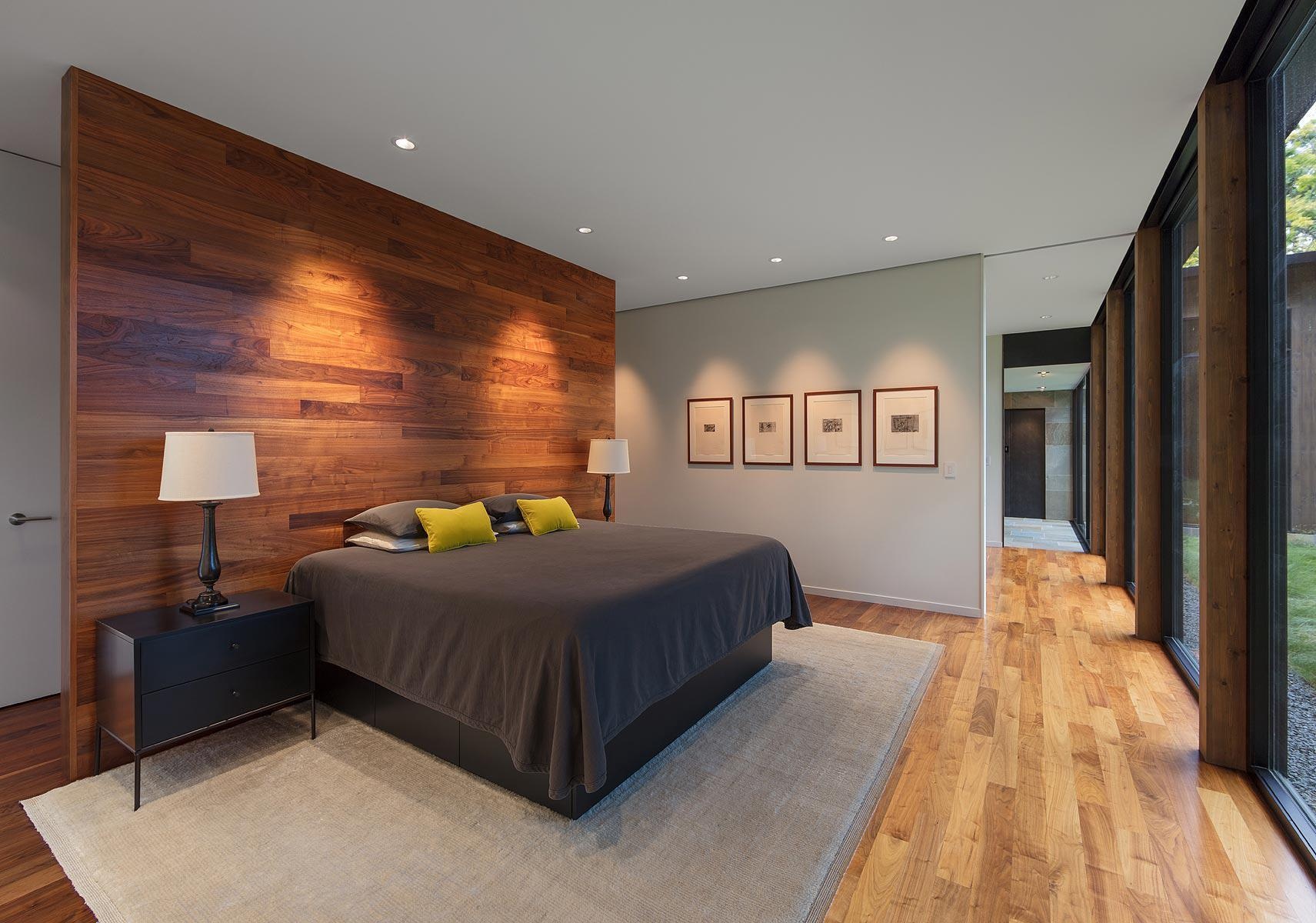 A warm wood accented master bedroom with views of trees and a peaceful layout.