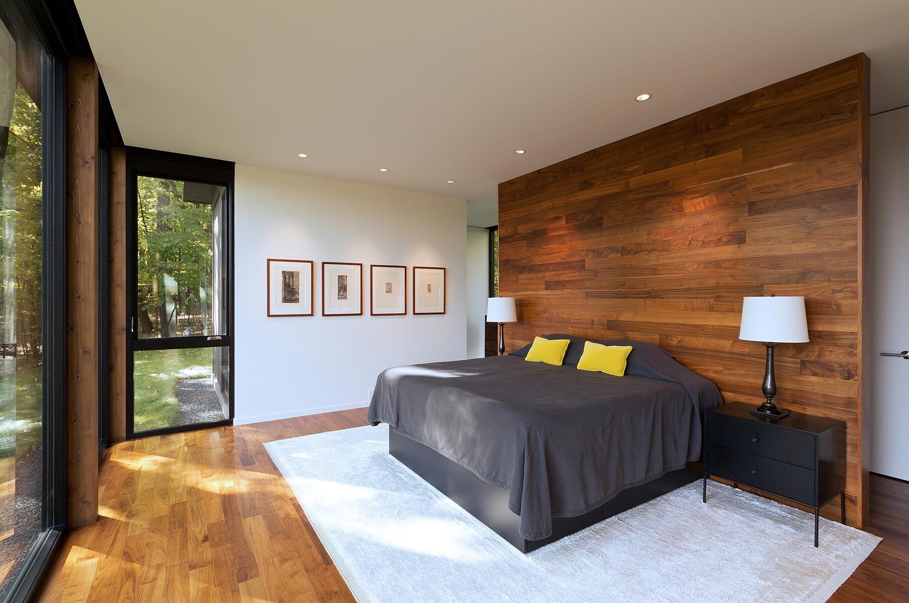 A warm wood accented master bedroom with views of trees and a peaceful layout.