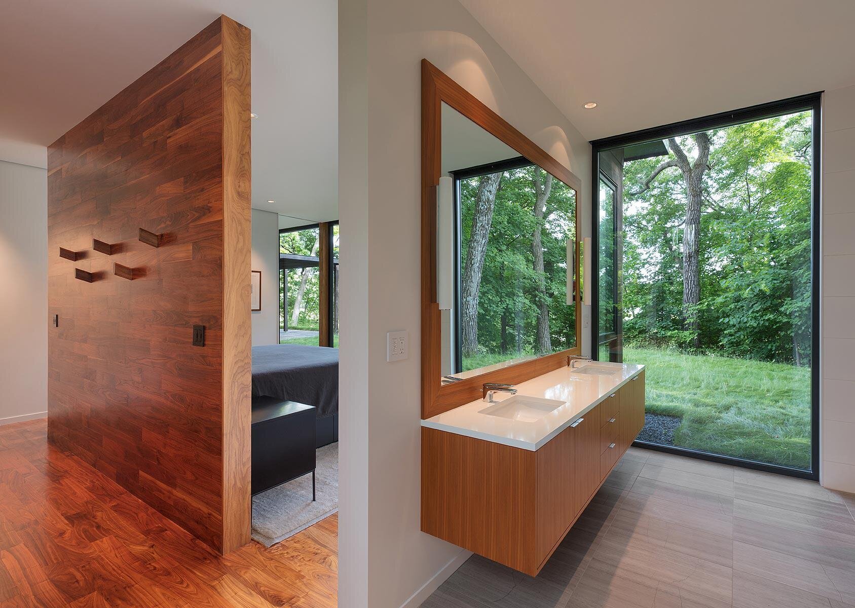 A warm wood accented master bedroom with views of trees and a peaceful layout.