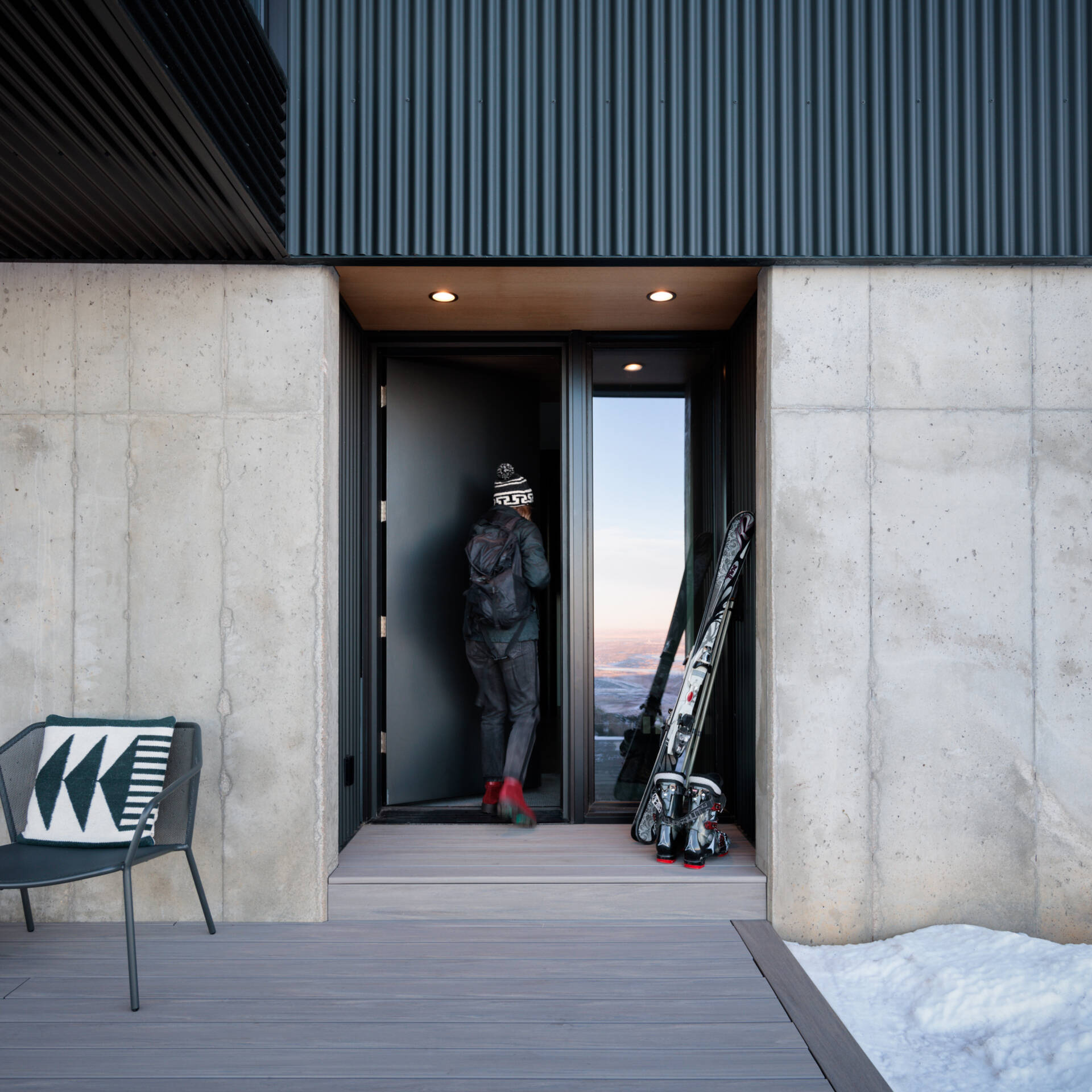 A sheltered entry porch sits beneath the cantilevered living room, creating a welcoming arrival that feels both practical and beautifully framed by the structure.