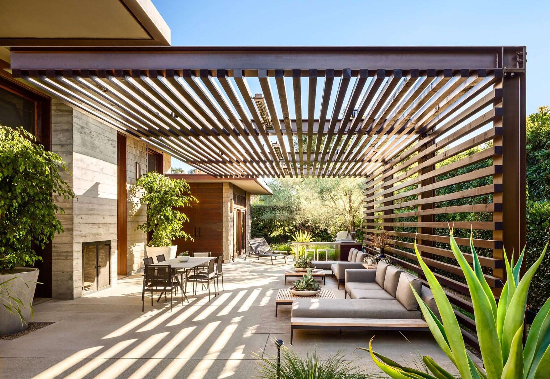 A pergola-topped outdoor lounge with fireplace and BBQ blends relaxation and California elegance.