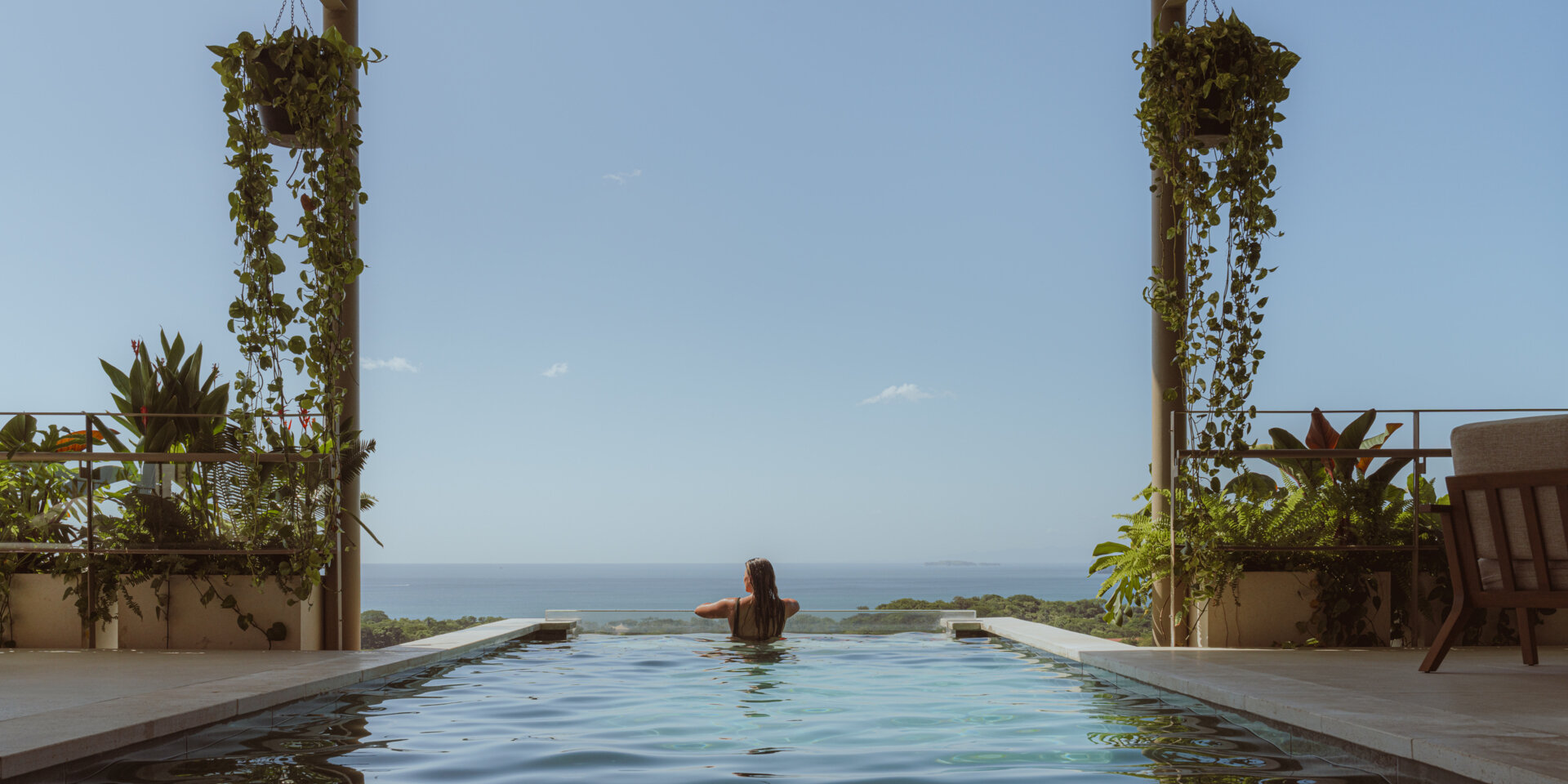 The cantilevered pool extends outward from the second floor, appearing to float in the canopy. Its position emphasizes the feeling of elevation the architecture is built around. As the water meets the edge, the view becomes a seamless extension of the home.