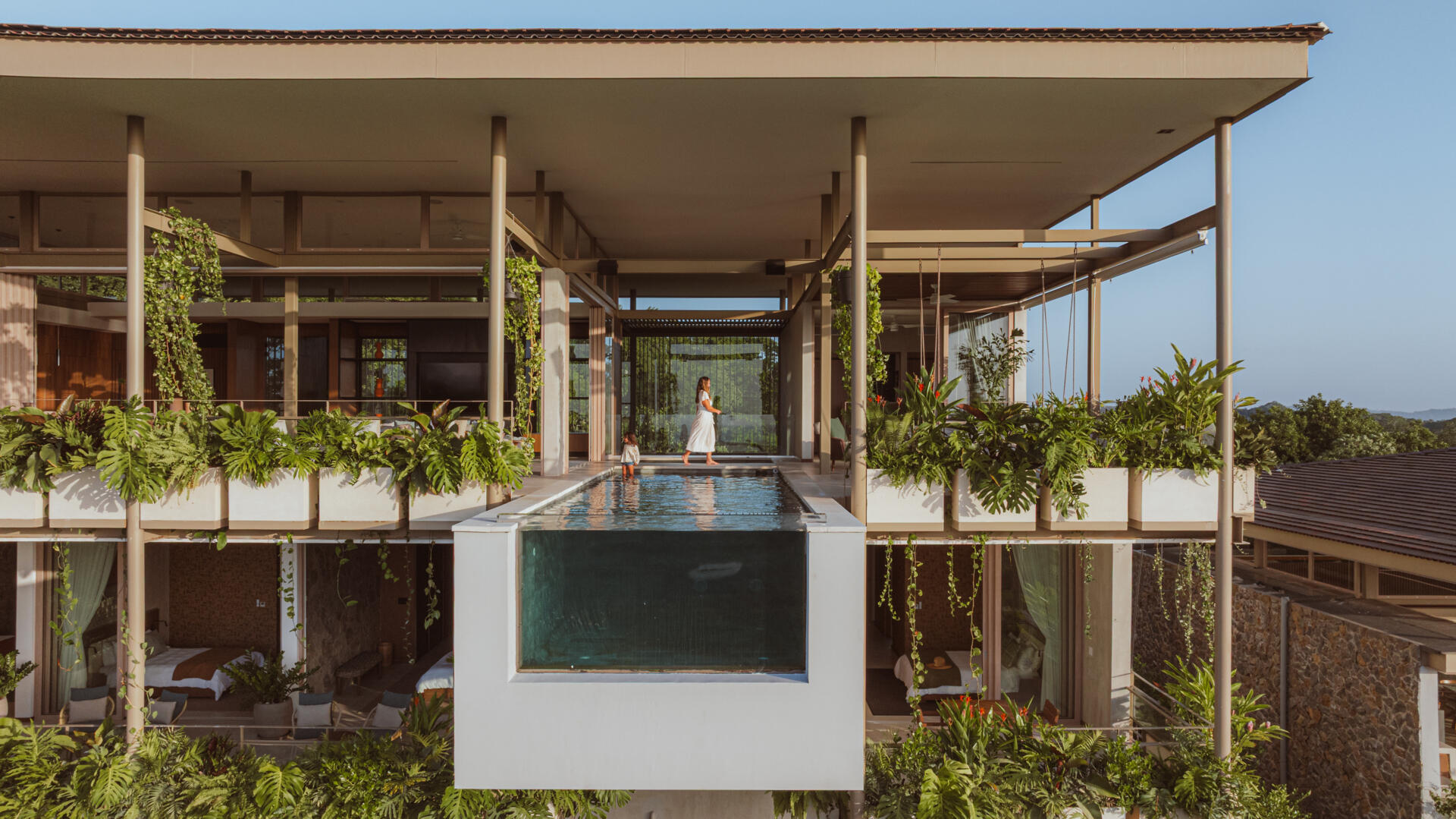 The cantilevered pool extends outward from the second floor, appearing to float in the canopy. Its position emphasizes the feeling of elevation the architecture is built around. As the water meets the edge, the view becomes a seamless extension of the home.