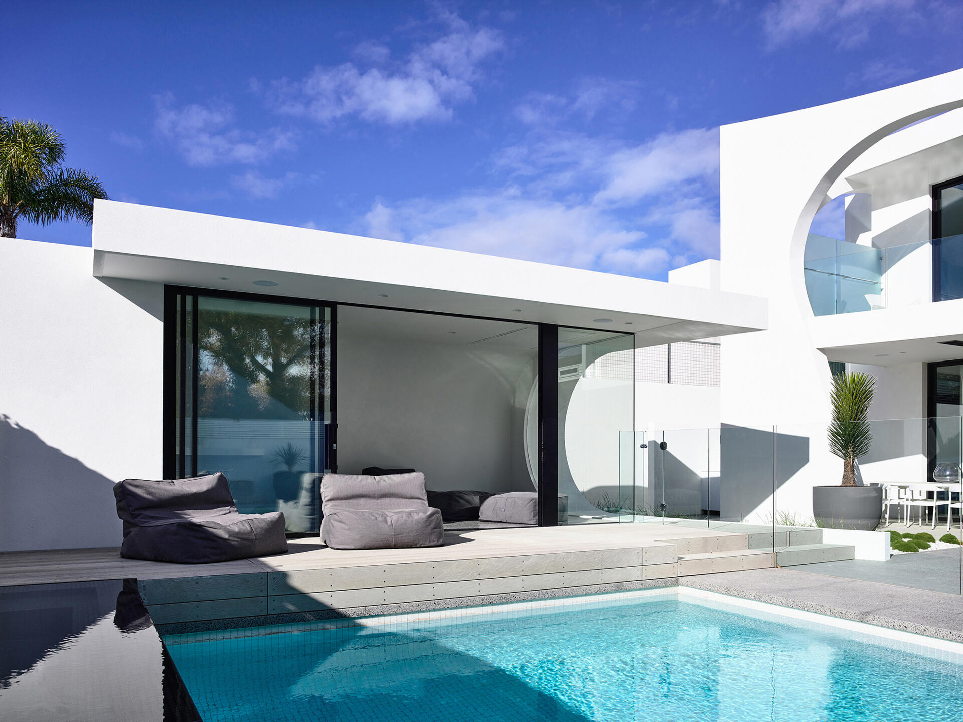 An infinity edge spa and pool sit beside a wave style pool house that offers shade and comfort after long days in the sun.