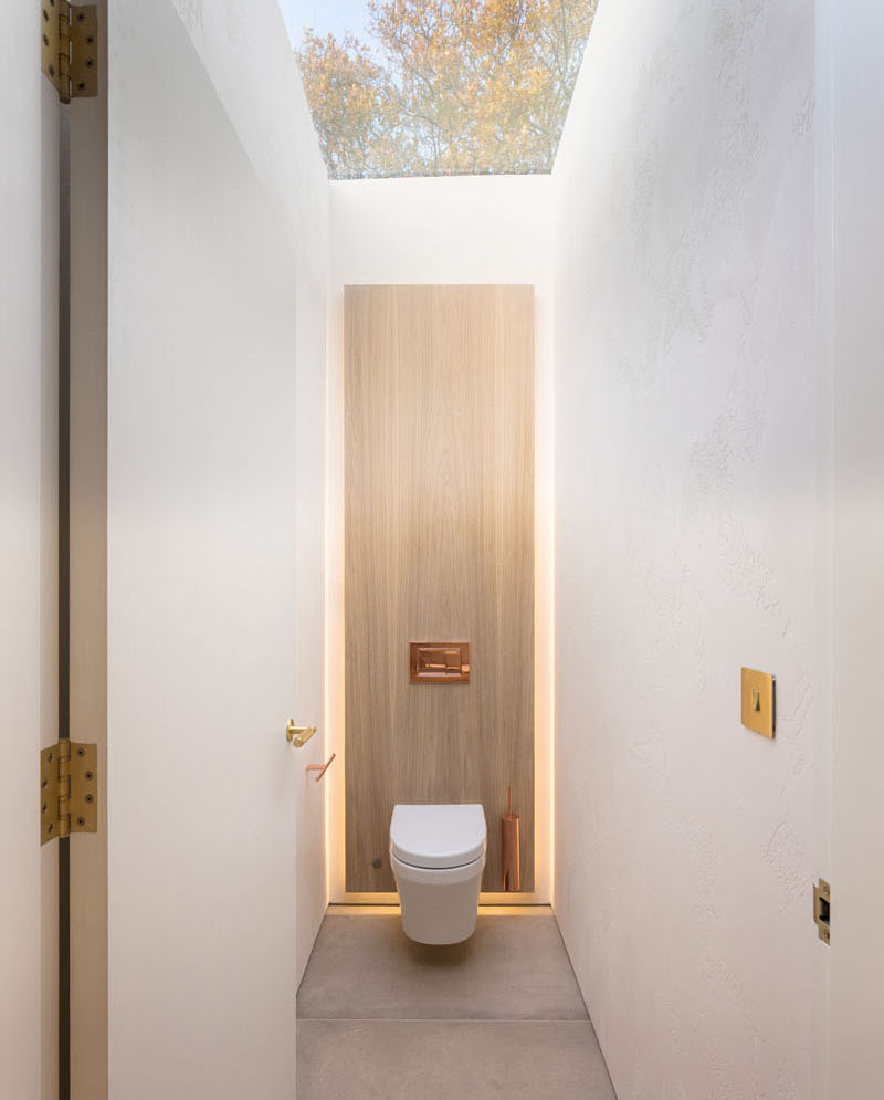 In the ensuite bathroom, a walk-in shower with a rainfall head and concealed lighting creates a spa-like calm. Subtle uplighting above the mirror enhances the gentle tones of the materials, while a skylight above the toilet area allows natural light to pour in, making even the smallest corner feel open.
