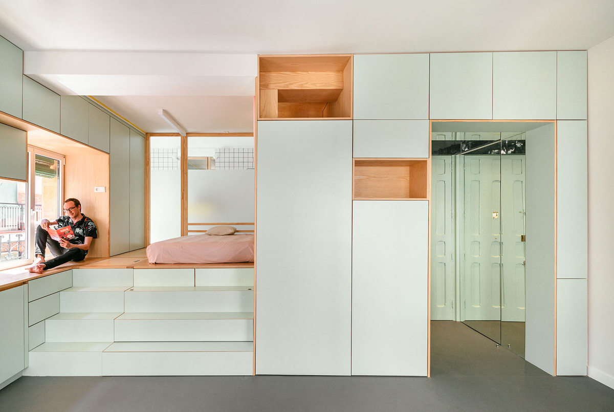 A tiny 355 square foot apartment in Madrid gets a clever two level makeover with mirrored walls, hidden storage, a raised bedroom, and a sunken spa style bath.