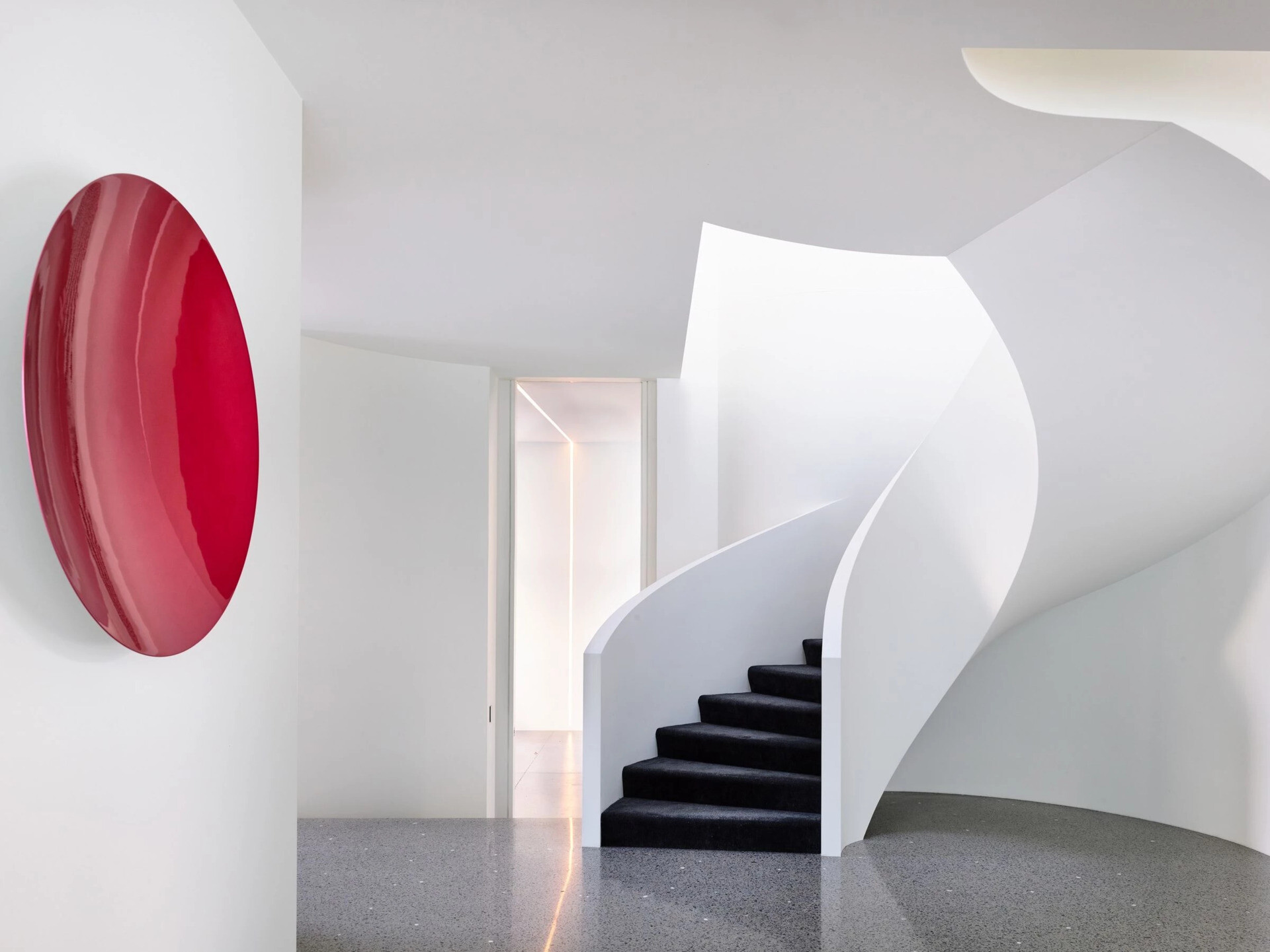 Custom spiral stairs with black treads and a circular skylight above create a sculptural moment inside the home.