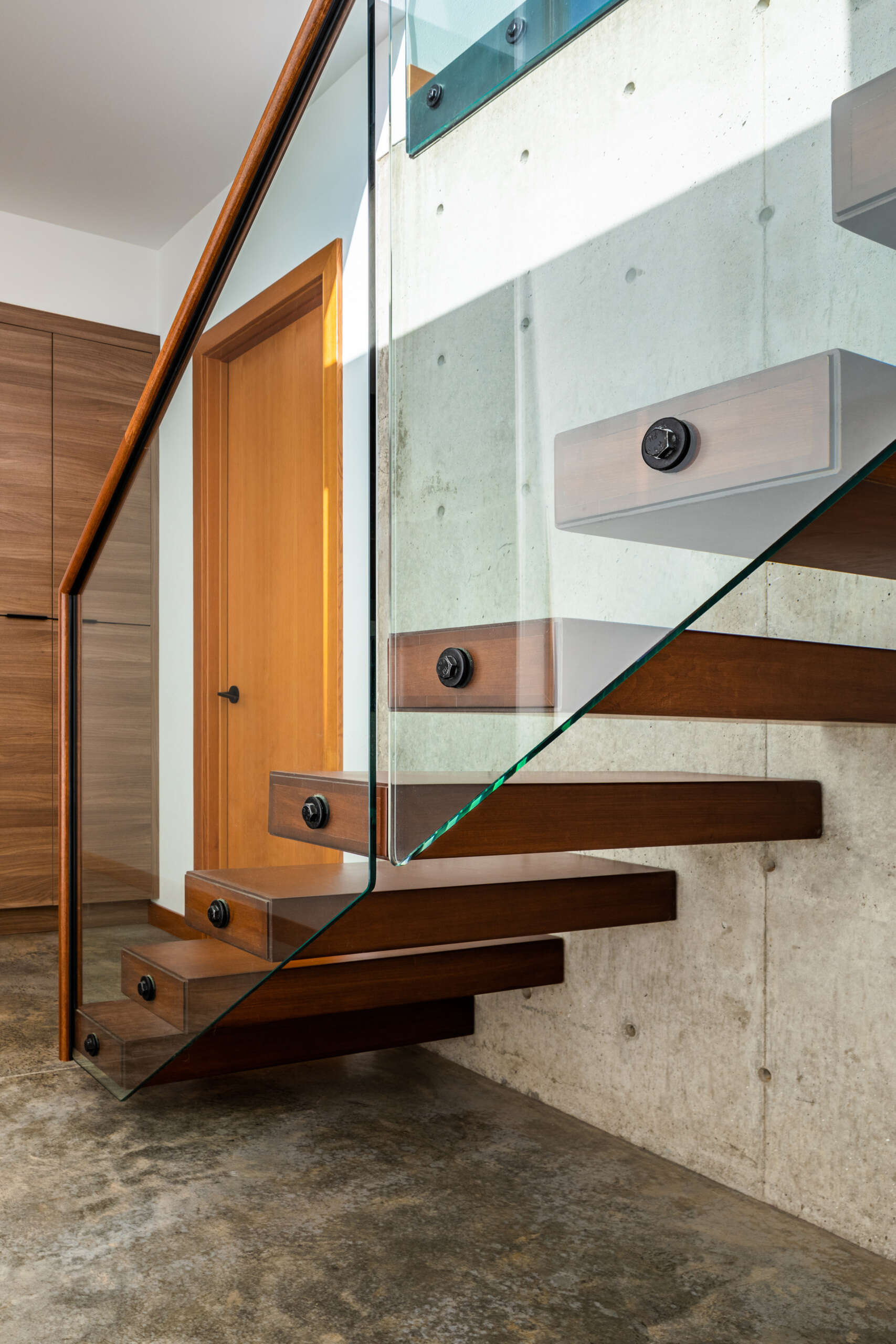 Una llamativa escalera flotante conecta los dos pisos y actúa como un divisor escultórico. Al descender a la terraza inferior se encuentra una sala familiar, una sala de literas y un espacio recreativo.