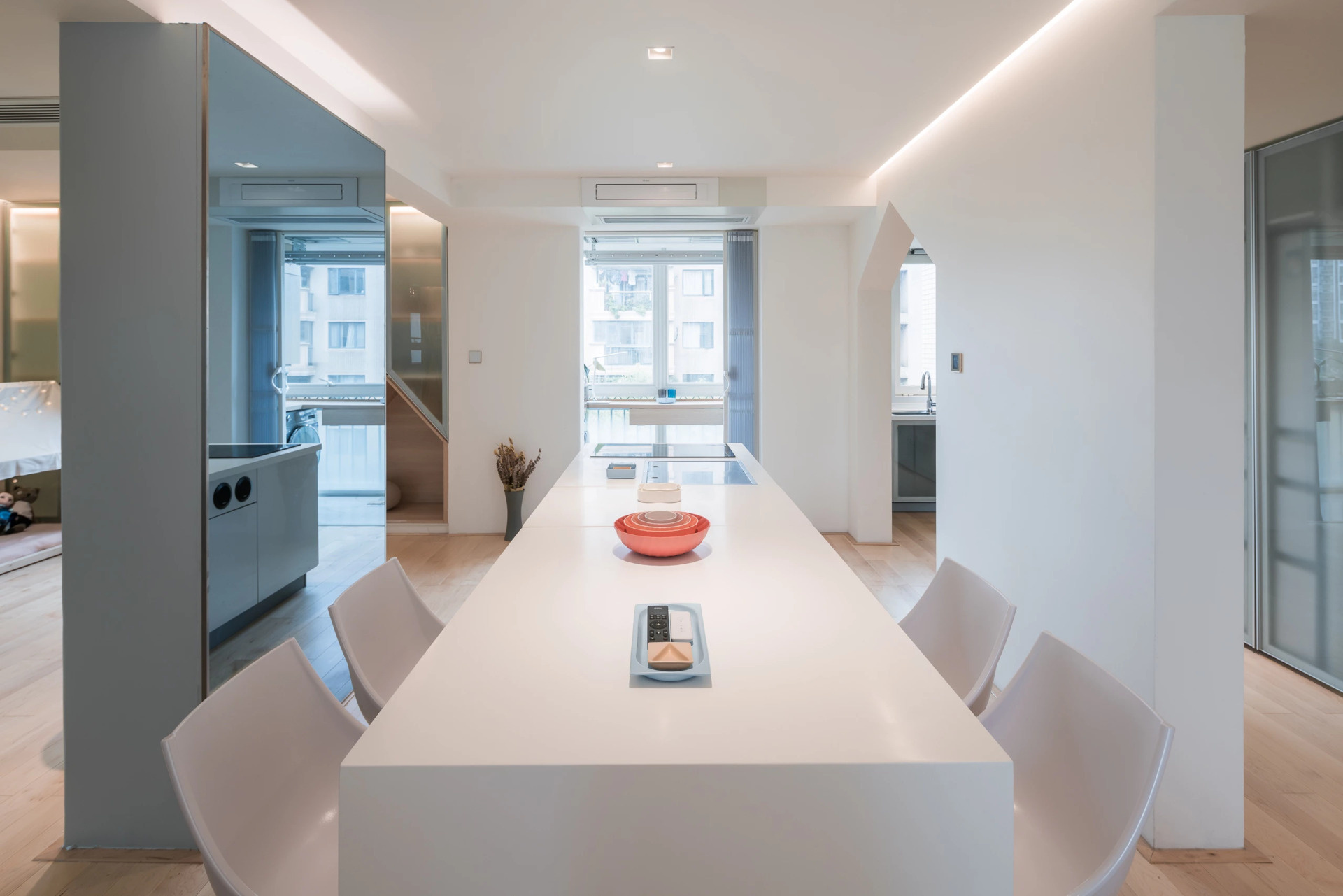 A white island kitchen with mirrored walls that turn meal prep into a social experience.