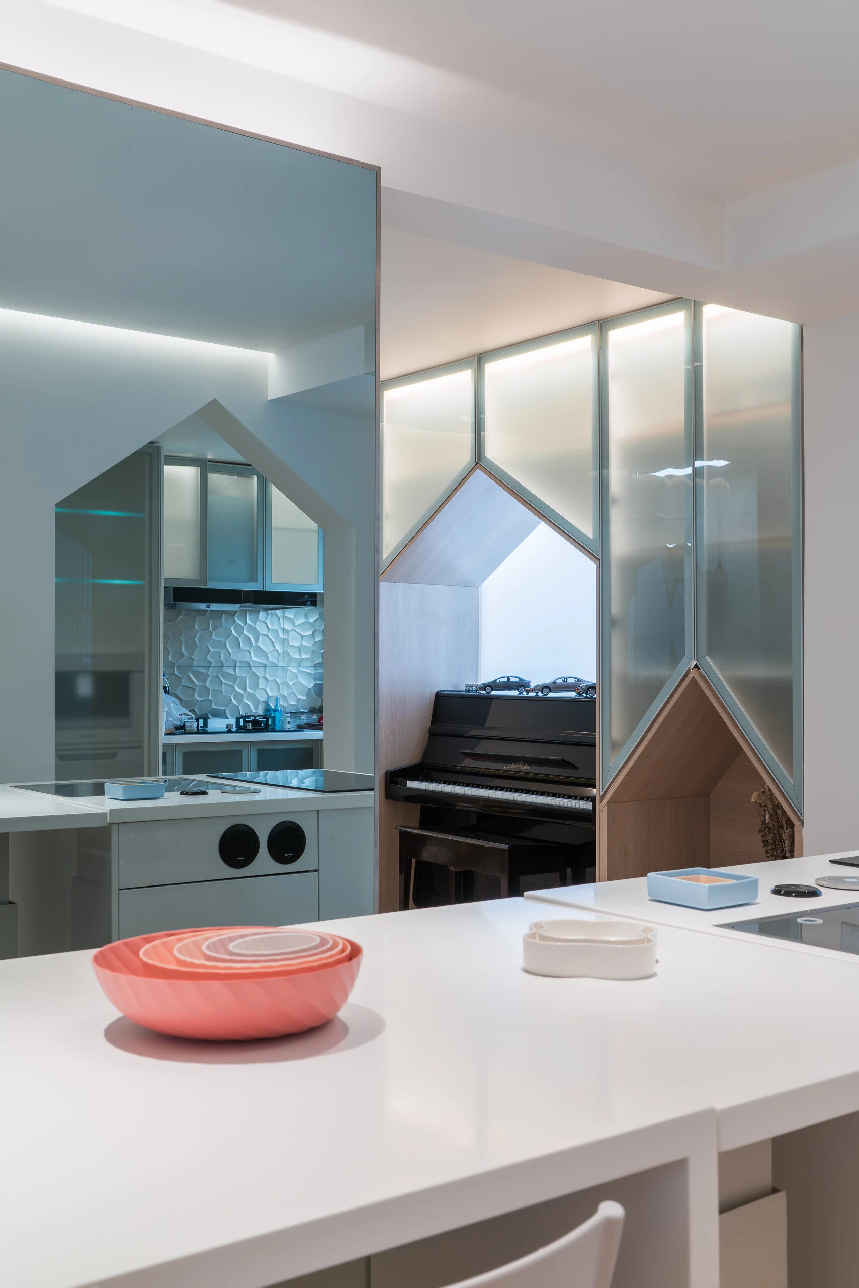 A white island kitchen with mirrored walls that turn meal prep into a social experience.