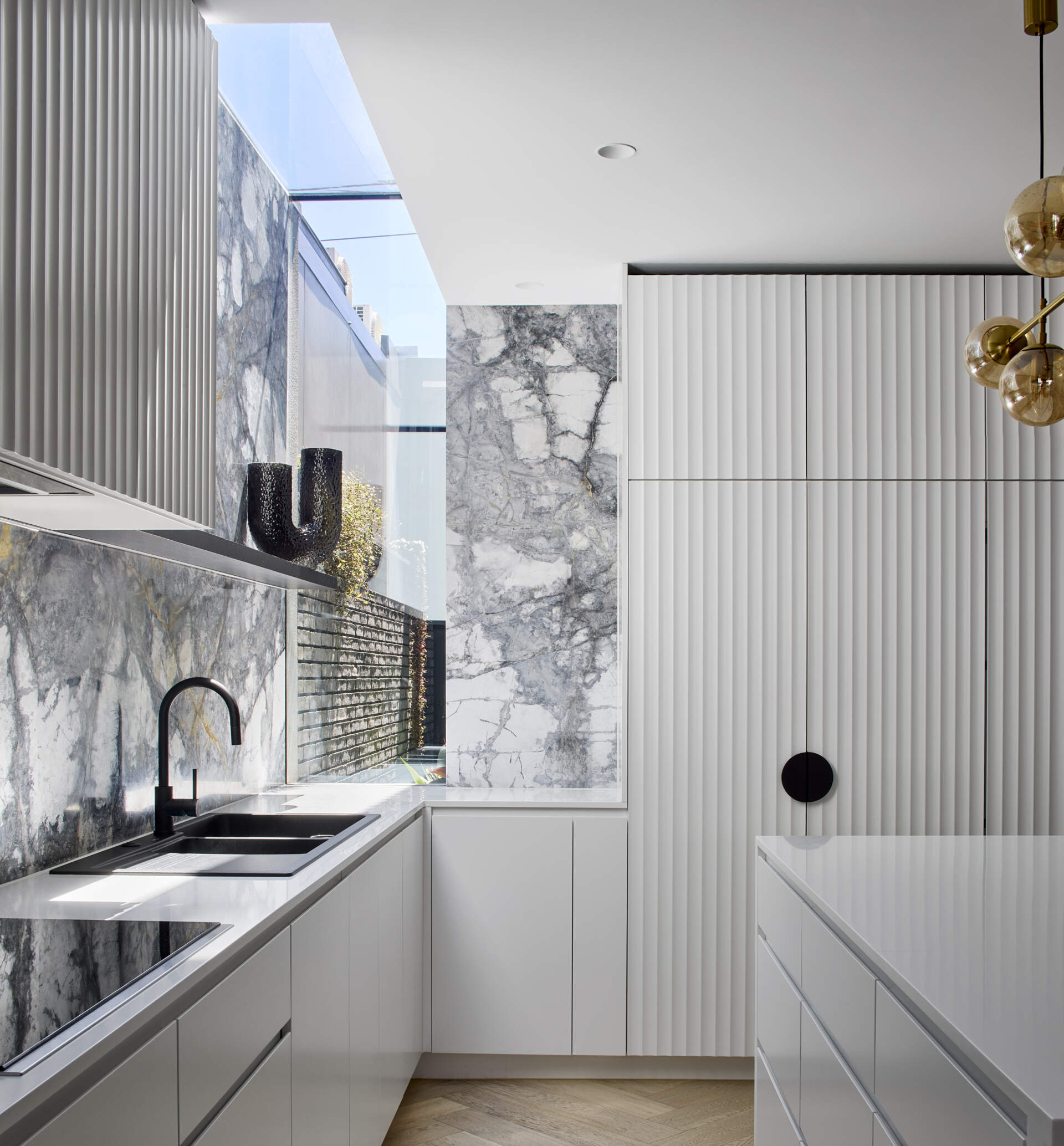 In this modern kitchen, a dramatic waterfall skylight pours daylight into what was once a dark corner.