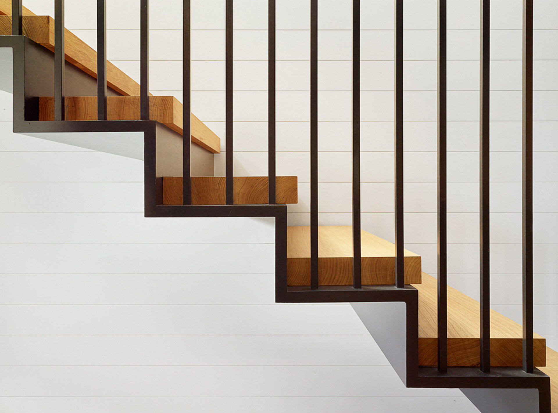 Wood and steel stairs lead to the private spaces above, where calm continues to rule.