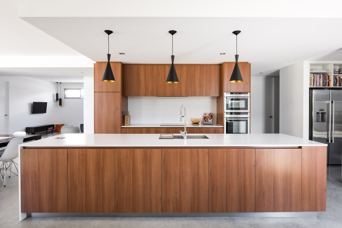 A bright kitchen where timber accents from the family booth carry through the cabinetry, balanced by fresh white counters.
