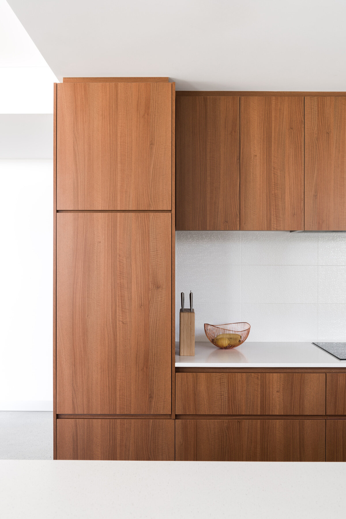 A bright kitchen where timber accents from the family booth carry through the cabinetry, balanced by fresh white counters.