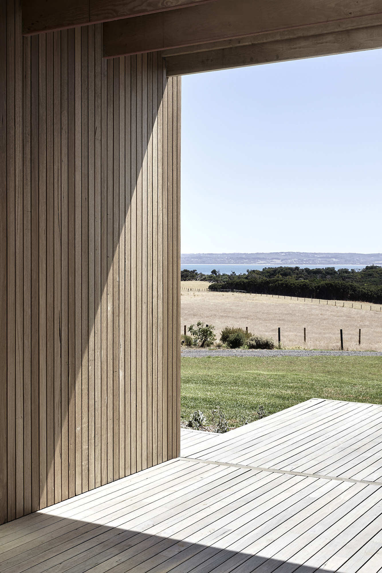 A central breezeway links the pavilions, creating a shared outdoor room that cools the home in summer and frames sea views in winter.