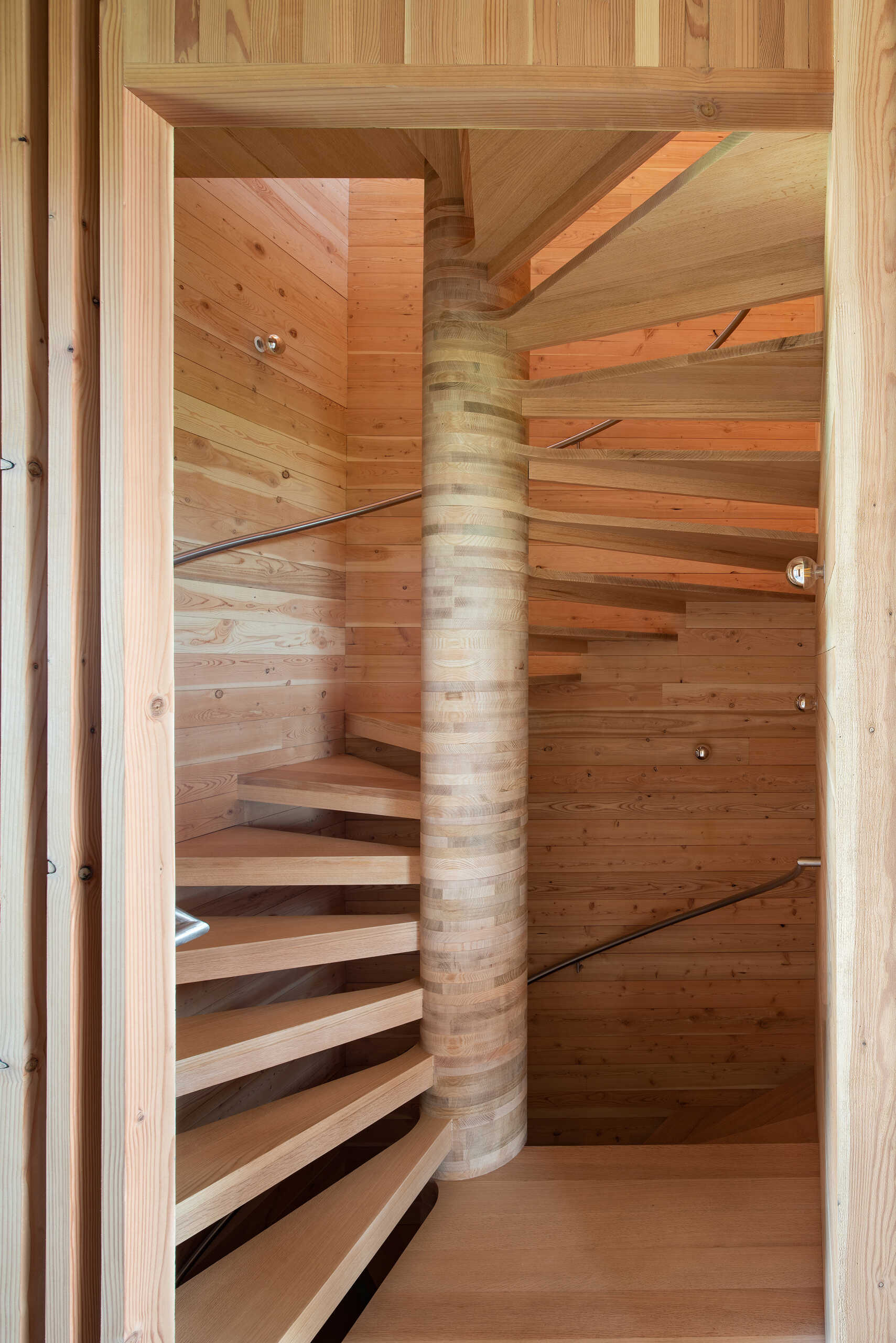 A handcrafted spiral staircase that doubles as sculpture, built from the same timber as the framing to keep the design cohesive and pure.