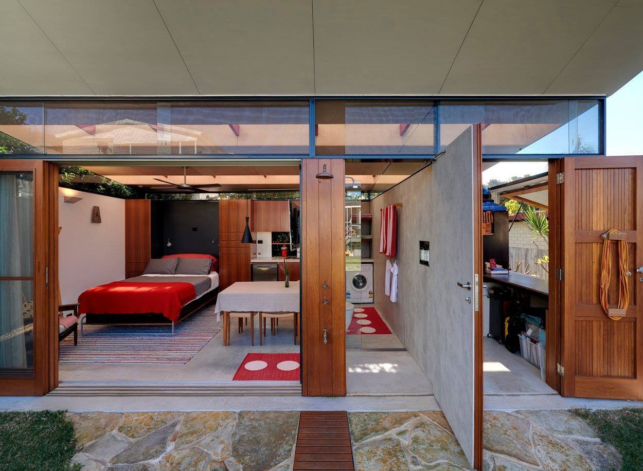 Pequeño estudio en el patio trasero con sala de estar, cocina americana, baño, lavandería y área de trabajo, todo diseñado para un uso diario flexible.