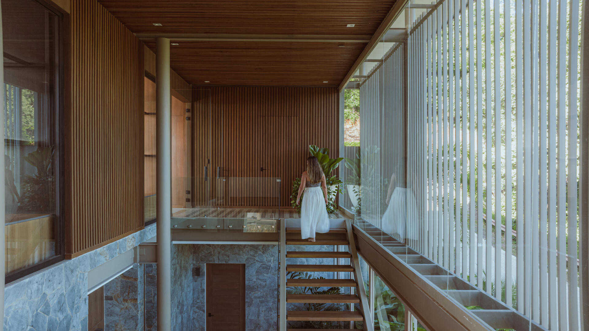 Inside the foyer, black and white tiles reference traditional Costa Rican patterns and connect the home to local craft. Cobalt blue armchairs introduce a bold moment of color that mirrors the tones of the sky and connects the interior to the surrounding landscape. From here, stairs guide the journey upward. The ascent reflects the concept of the home, with each step revealing wider views and lighter materials.