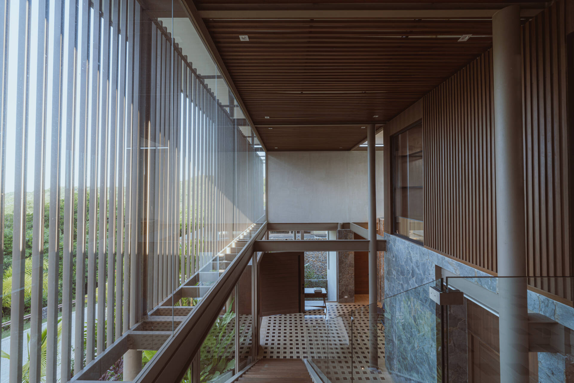 Inside the foyer, black and white tiles reference traditional Costa Rican patterns and connect the home to local craft. Cobalt blue armchairs introduce a bold moment of color that mirrors the tones of the sky and connects the interior to the surrounding landscape. From here, stairs guide the journey upward. The ascent reflects the concept of the home, with each step revealing wider views and lighter materials.