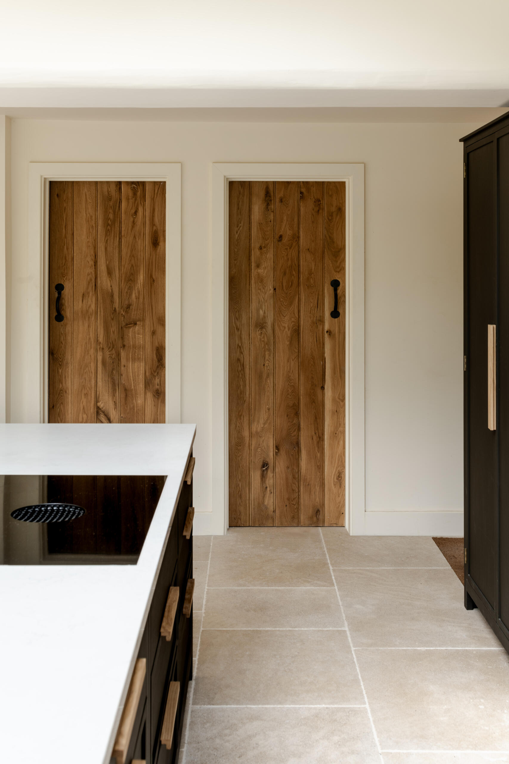 The kitchen sits within the open plan arrangement, using the new glazing and steel details to add clarity and simplicity while keeping the palette restrained. The dark kitchen cabinets complement the window frames and offer contrast to the light interior, while a skylight adds natural light.