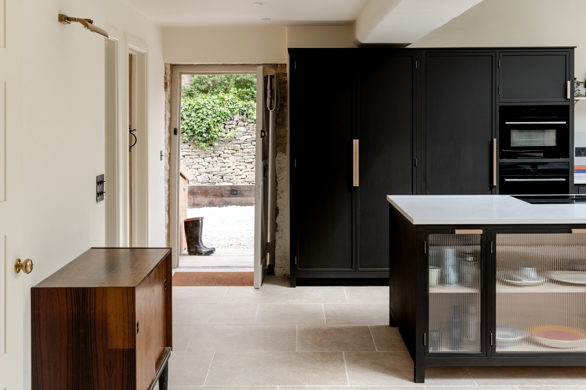 The kitchen sits within the open plan arrangement, using the new glazing and steel details to add clarity and simplicity while keeping the palette restrained. The dark kitchen cabinets complement the window frames and offer contrast to the light interior, while a skylight adds natural light.