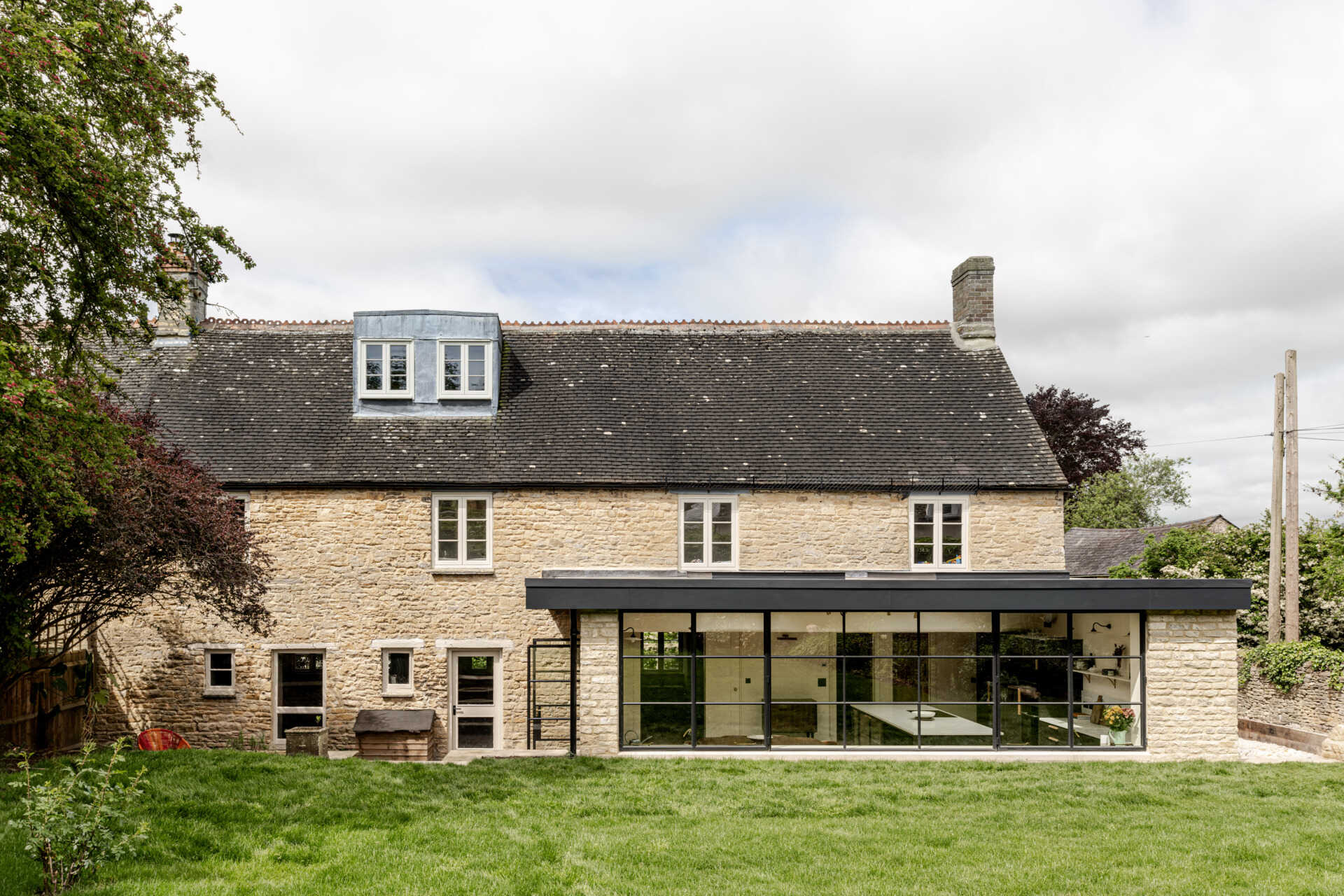 The extension sits at the rear as a low, single storey volume. By sinking it slightly into the garden, its profile stays subtle, reducing its visibility to neighbours and protecting views within the Charlbury Conservation Area. Slim steel framing, large glazing, and Cotswold stone create a gentle dialogue between old and new.