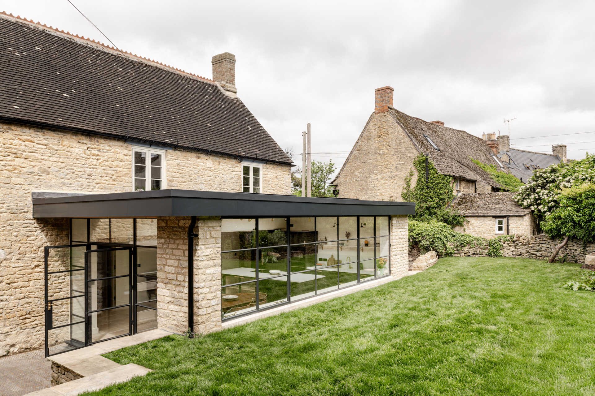 The extension sits at the rear as a low, single storey volume. By sinking it slightly into the garden, its profile stays subtle, reducing its visibility to neighbours and protecting views within the Charlbury Conservation Area. Slim steel framing, large glazing, and Cotswold stone create a gentle dialogue between old and new.
