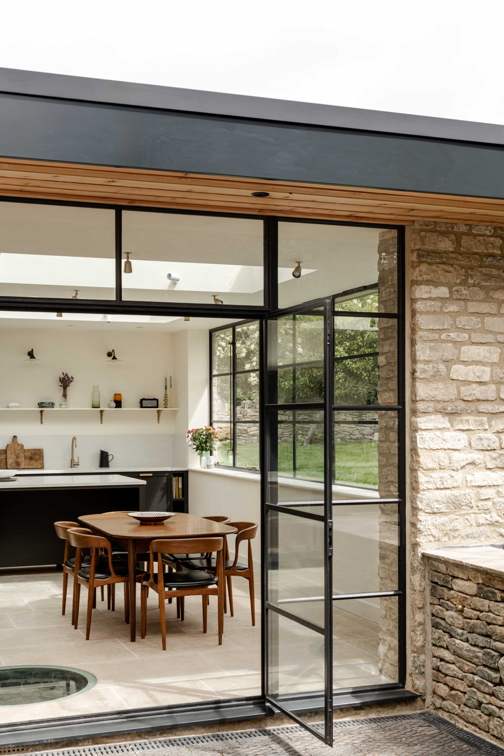 The extension sits at the rear as a low, single storey volume. By sinking it slightly into the garden, its profile stays subtle, reducing its visibility to neighbours and protecting views within the Charlbury Conservation Area. Slim steel framing, large glazing, and Cotswold stone create a gentle dialogue between old and new.