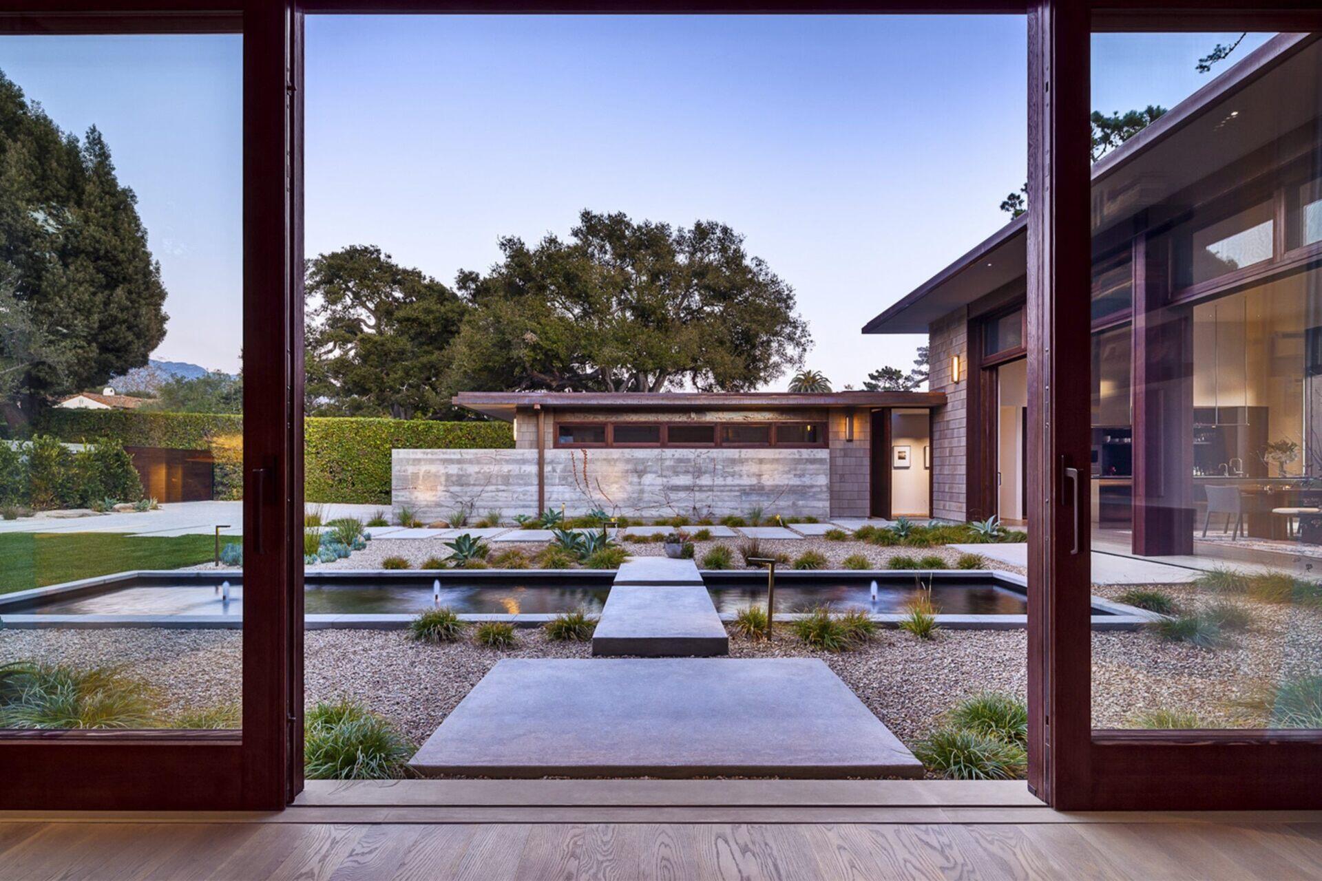 A serene Montecito courtyard with water, stone, and greenery creates a tranquil welcome to this modern home.