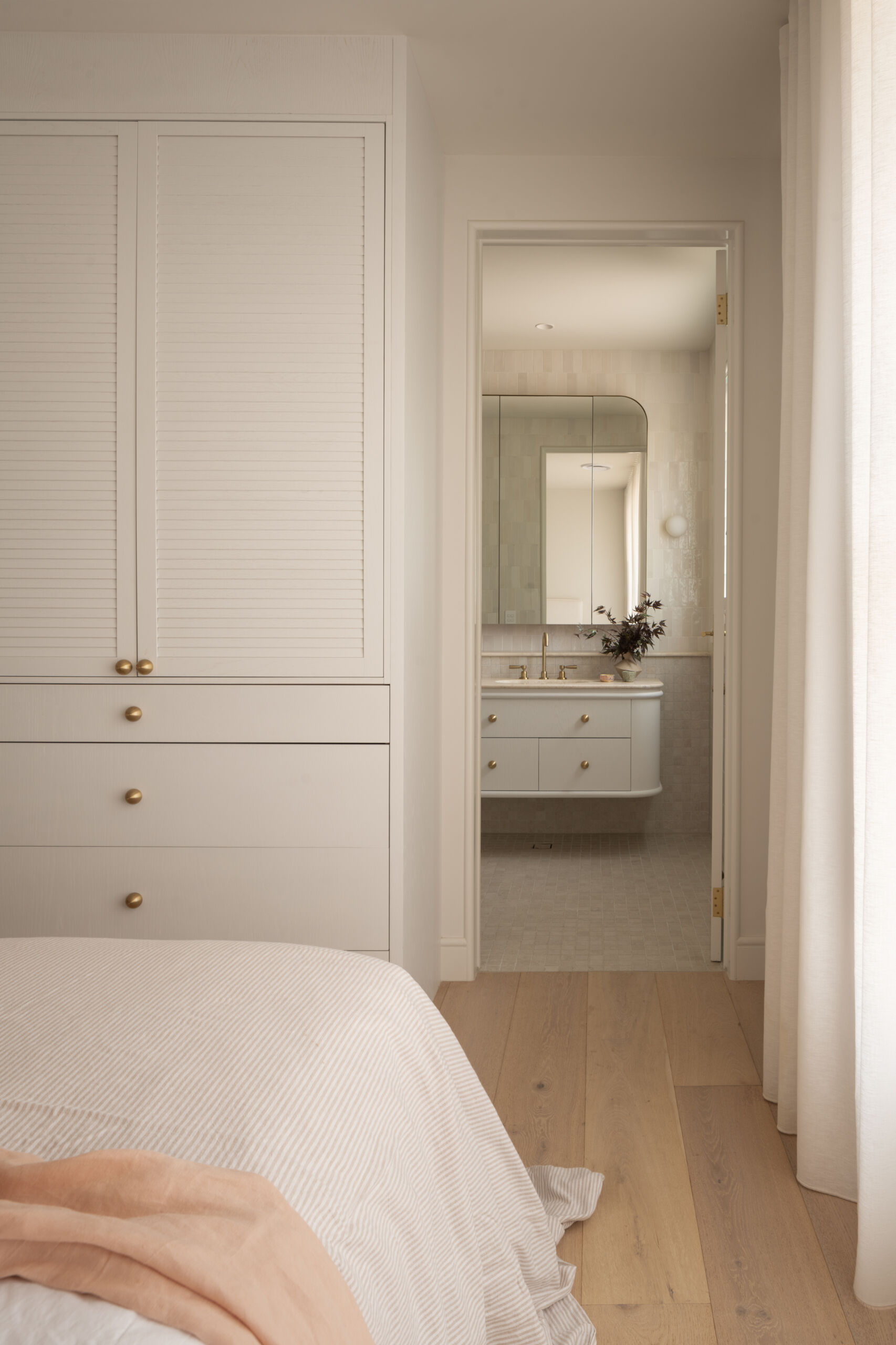 A modern guest bedroom with built-in closets and a bathroom with curves and Travertine details.