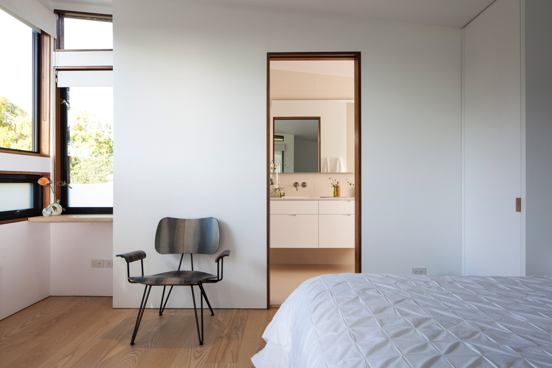 The primary bedroom suite combines large windows, built-in storage, and a bright ensuite with porcelain tiles for a serene retreat.