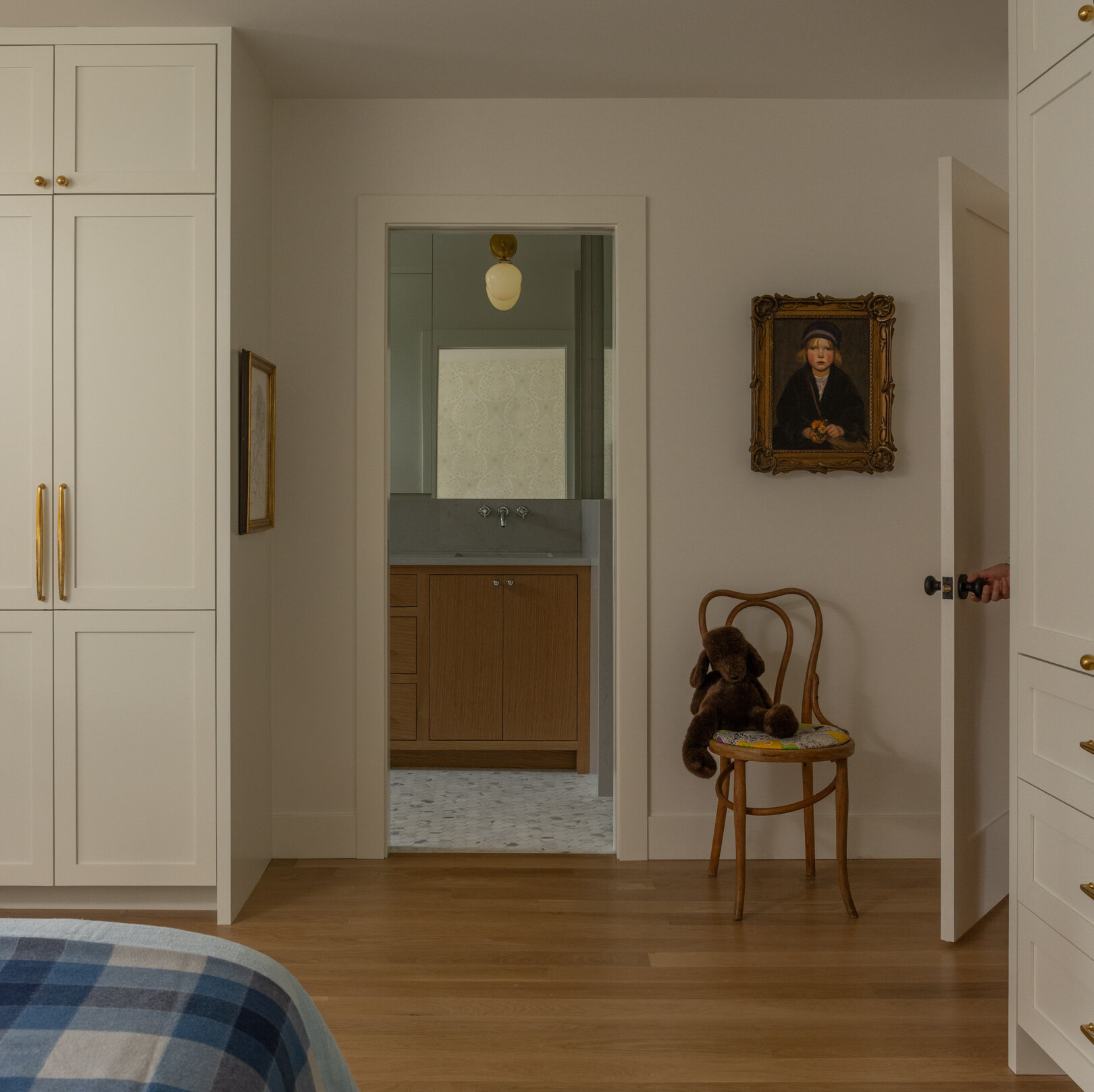 Esta suite principal fue diseñada pensando en la eficiencia y la tranquilidad. Los gabinetes estilo shaker del piso al techo reemplazan a los voluminosos armarios tradicionales y brindan un espacio de almacenamiento cohesivo sin ser pesado. Este enfoque integrado continúa el enfoque de la casa en líneas limpias y continuidad.