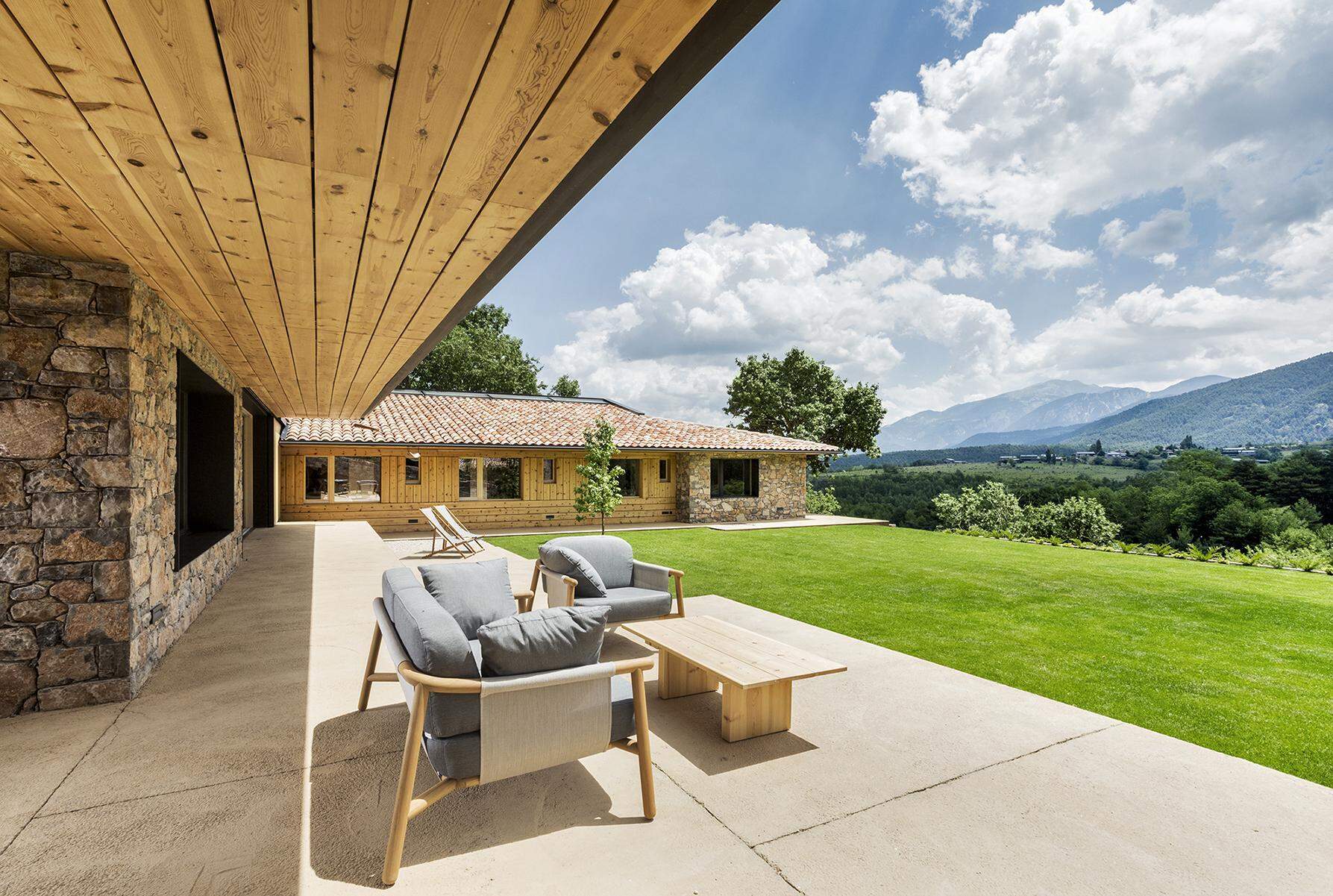 Sliding doors open to a covered porch and grassy backyard with views of the Cadí-Moixeró Natural Park.