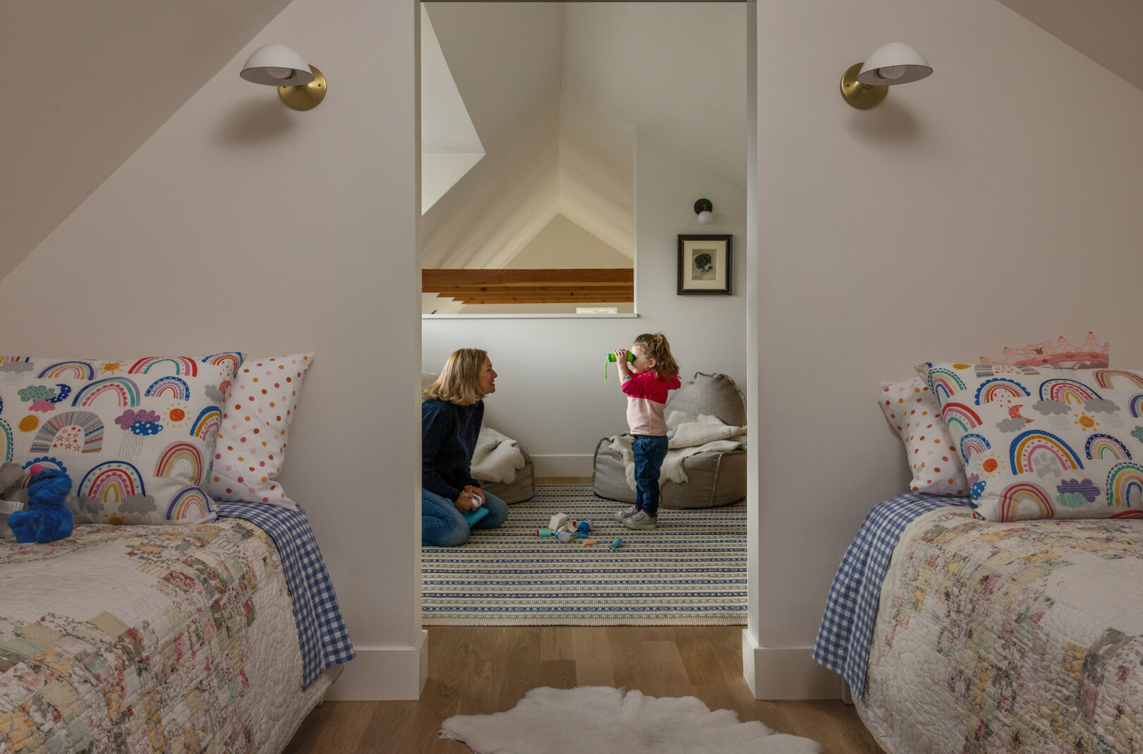 Un espacio tipo loft tallado debajo de la buhardilla orientada al sur sirve como un cómodo dormitorio, perfecto para visitar a los nietos. La luz cálida se filtra, creando una sensación de escape aislado que es a la vez divertida y pacífica.