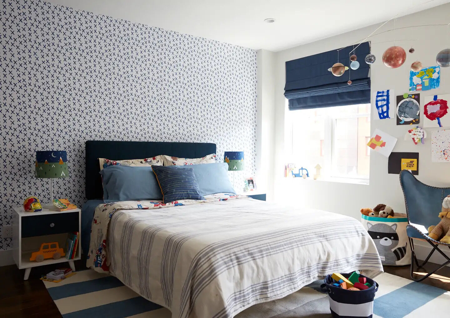 Graphic wallpaper and blue accents add personality and playfulness to this bedroom.