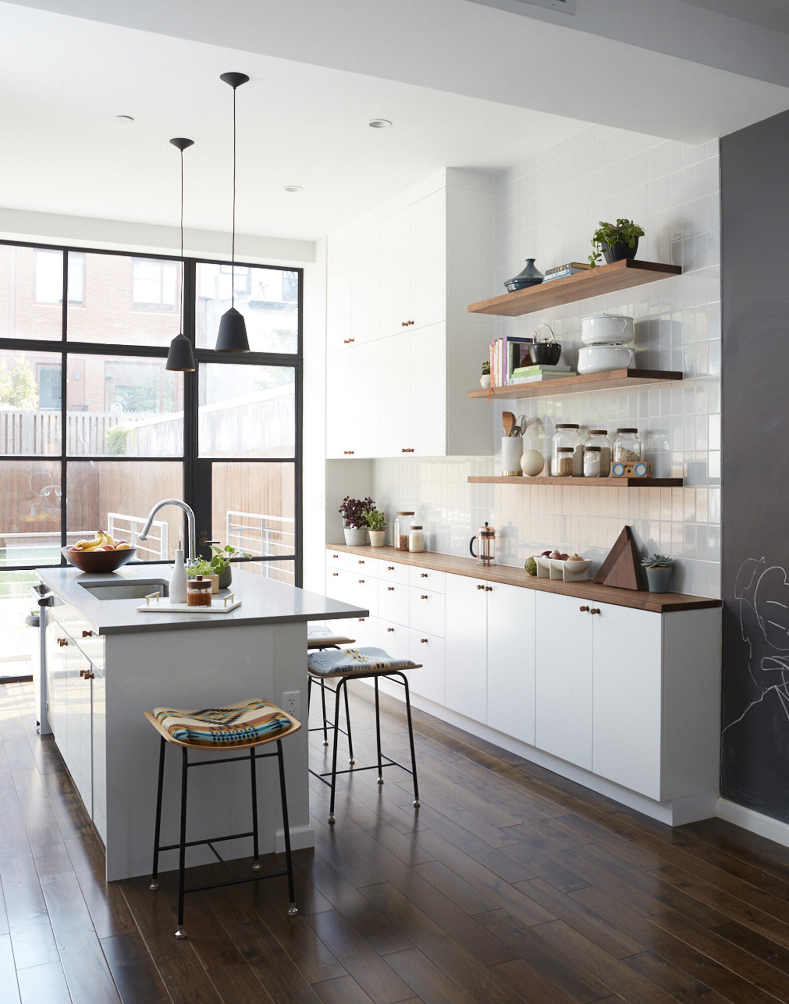 White subway tiles laid vertically pair with wood shelves and counters for a bright yet grounded kitchen design.