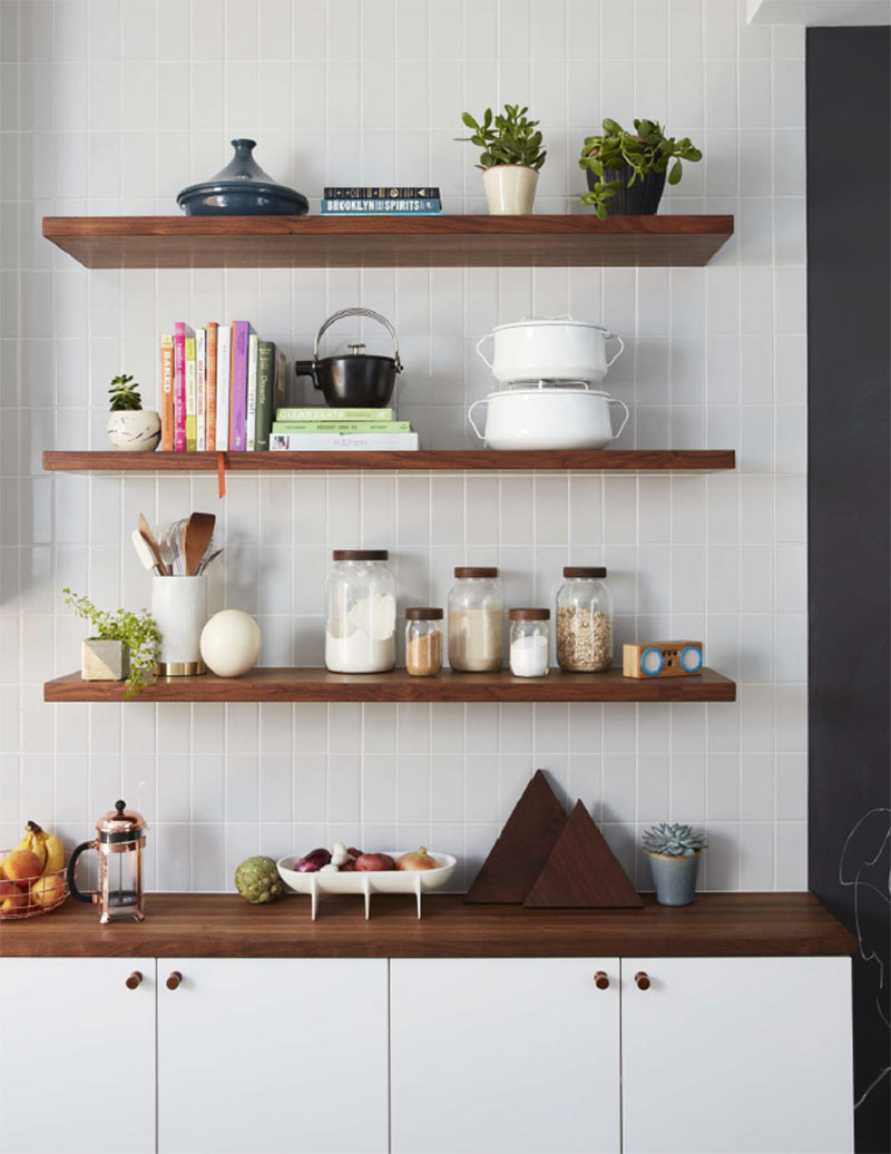 White subway tiles laid vertically pair with wood shelves and counters for a bright yet grounded kitchen design.