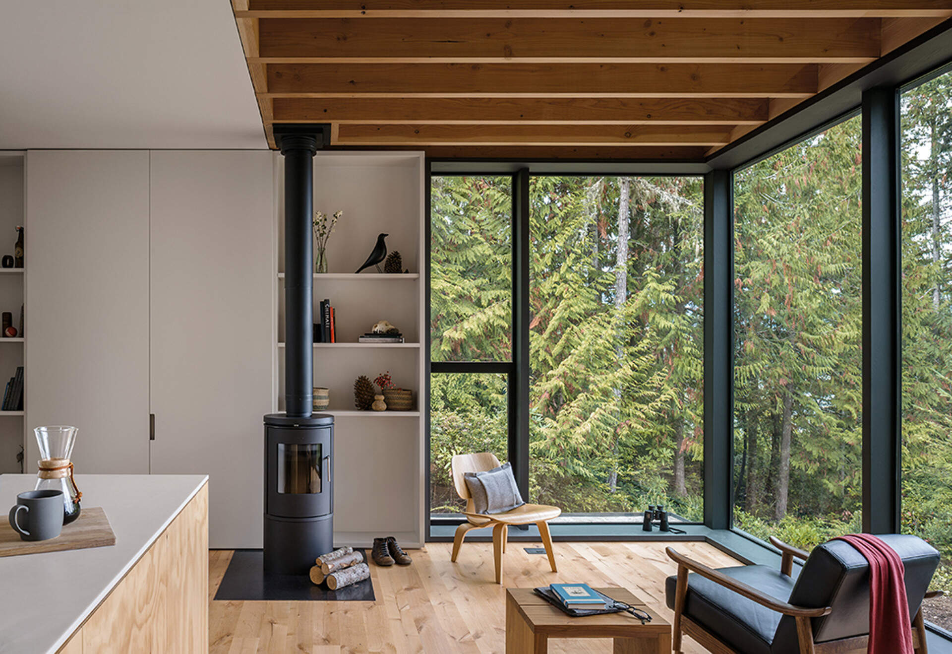 Light warm interiors with pine plywood and full height windows that make a small cabin feel spacious and inviting.