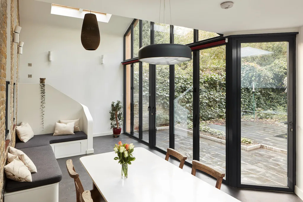 A garden facing dining area with folding glass doors that blur the line between indoor comfort and outdoor living.