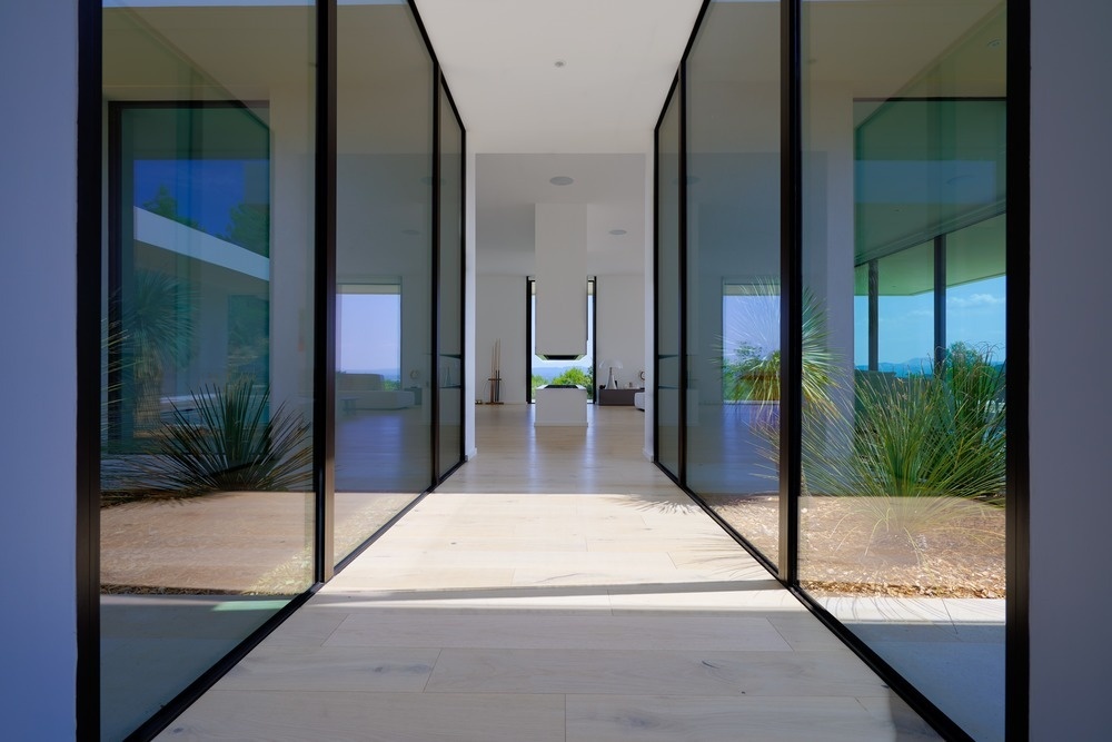 A floor to ceiling glass corridor connects the buildings, turning a simple hallway into a garden viewing experience.