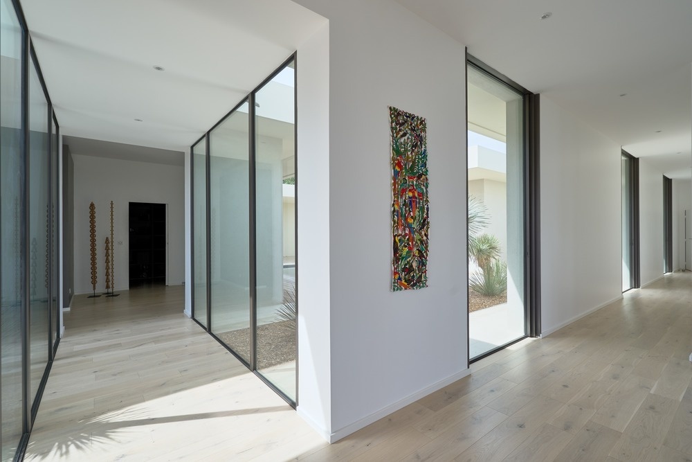 White walls, light wood floors and expansive glazing create bright, understated interiors throughout the home.