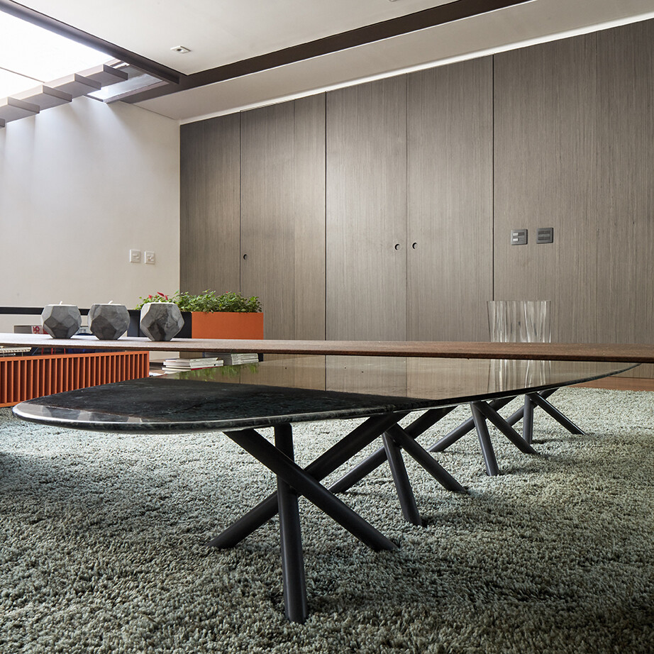 A wood accent wall runs along the upper floor, introducing warmth while discreetly concealing doors to the bedroom and a powder room. The design keeps the space uncluttered, with storage and circulation integrated seamlessly into the architecture.